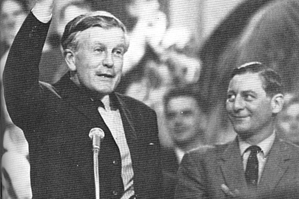 Black and white photograph showing Jo Grimond (Leader of the Liberal Party, 1956–67), his right hand raised above his head as he addresses a crowd. Next to him, smiling at Grimmond, is with Eric Lubbock, winner of the Orpington by-election in 1962