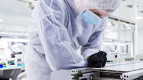 Person wearing protective equipment in a laboratory or high-tech factory.