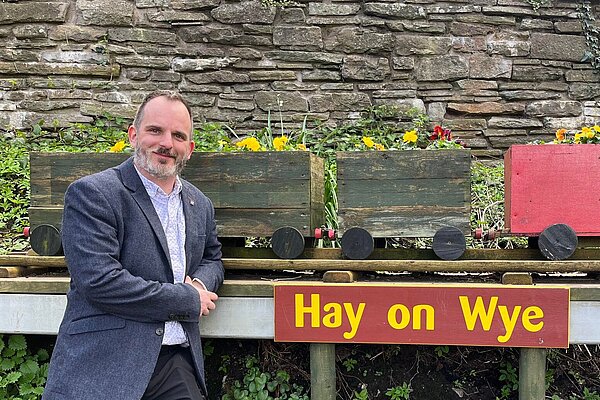 Gareth Ratcliffe by a sign reading Hay on Wye