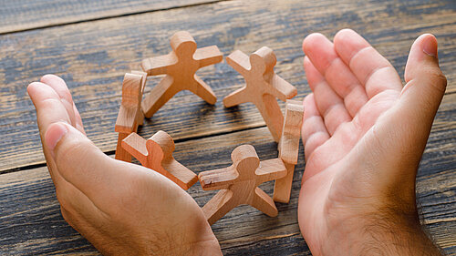 Hands surrounding wooden figures