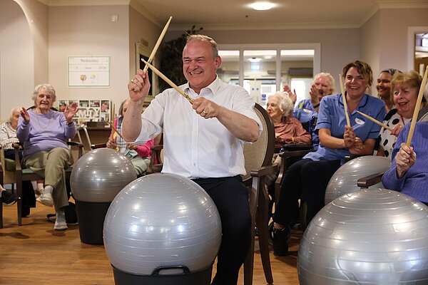 Ed Davey takes part in a drumming session at a care home