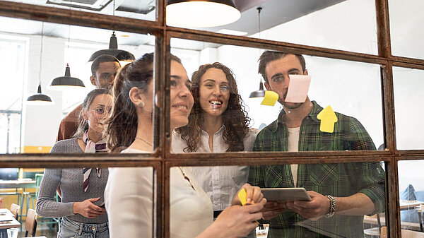 Five people looking a board with post-it notes